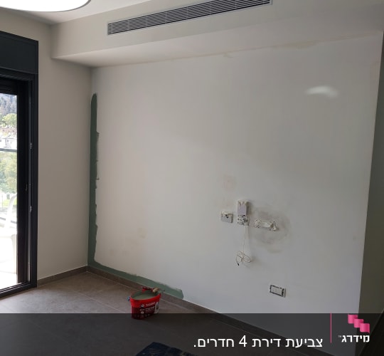 קיר צבוע חלקית עם דלי צבע על הרצפה